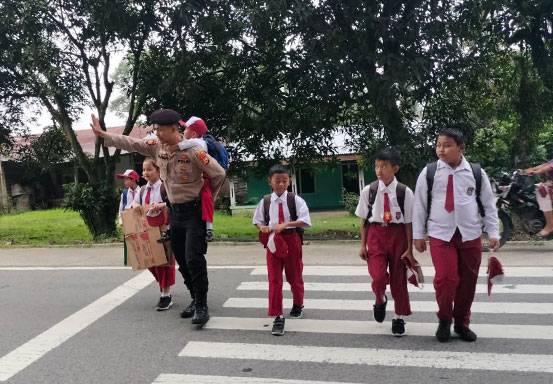 Keren! Polisi Ini Gendong Anak Sekolah Seberangi Jalan